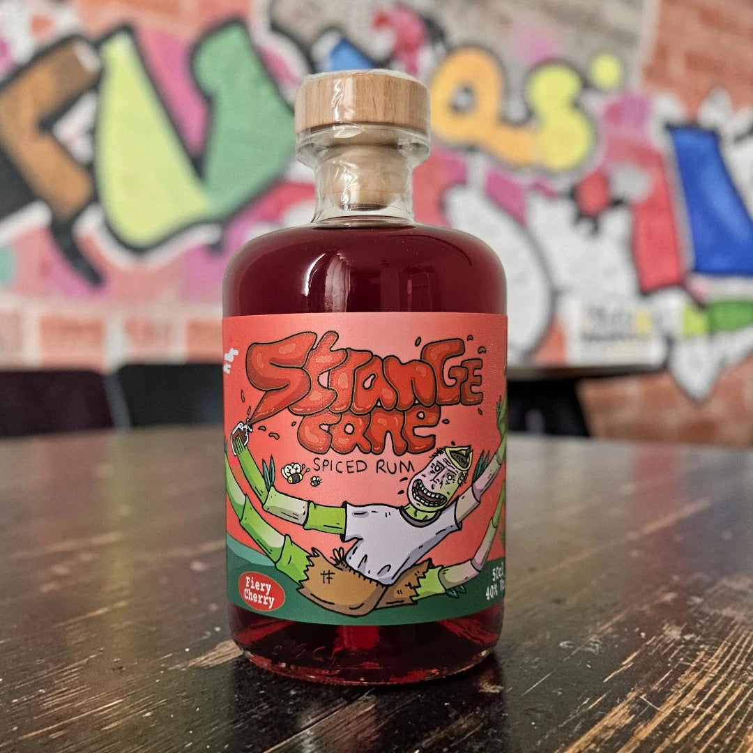 Strange Cane Fiery Cherry spiced rum on wooden table with graffiti wall