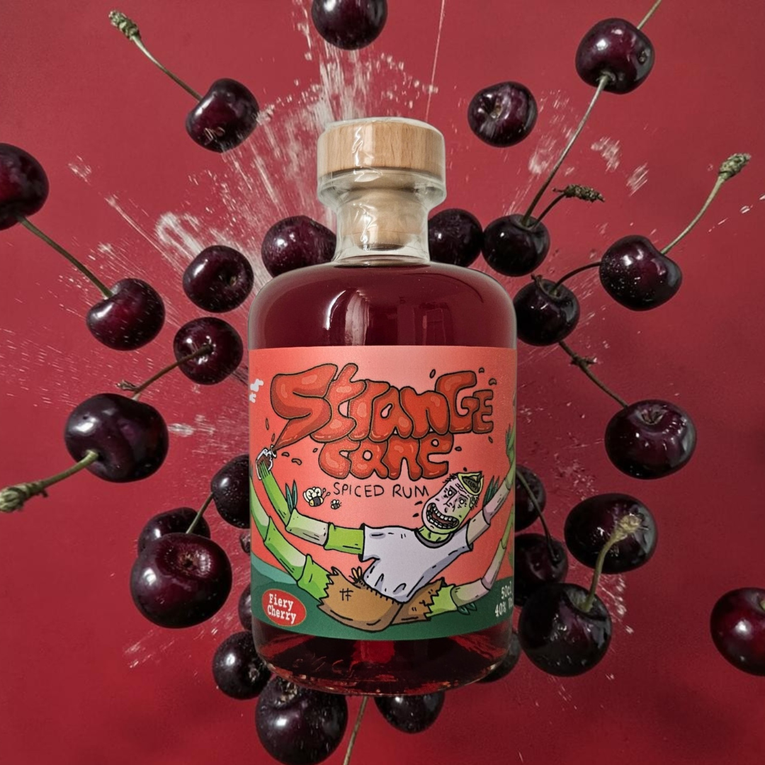 Strange Cane Fiery Cherry spiced rum on a red background with bursting fresh cherries