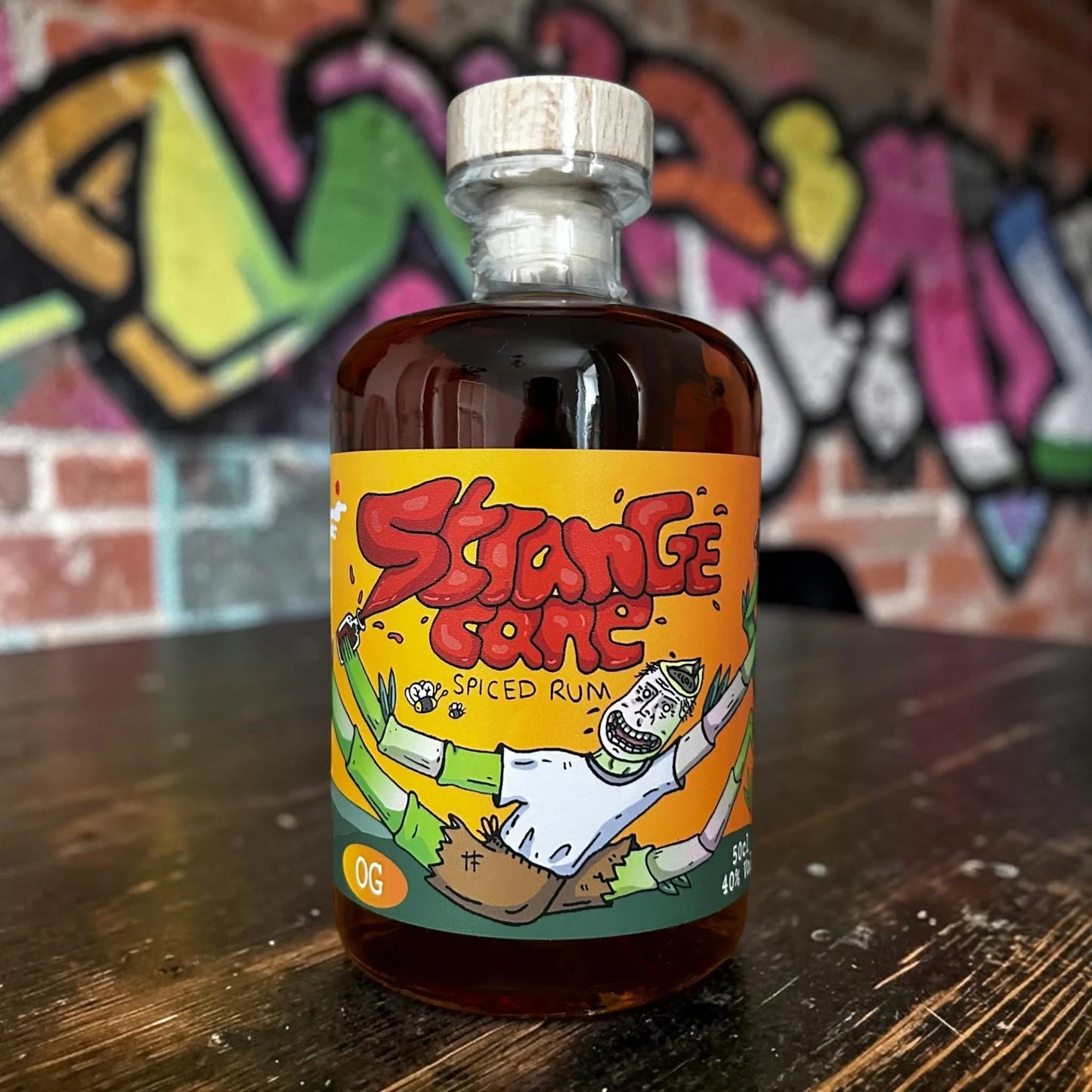 Strange Cane OG spiced rum on wooden table with graffiti wall 